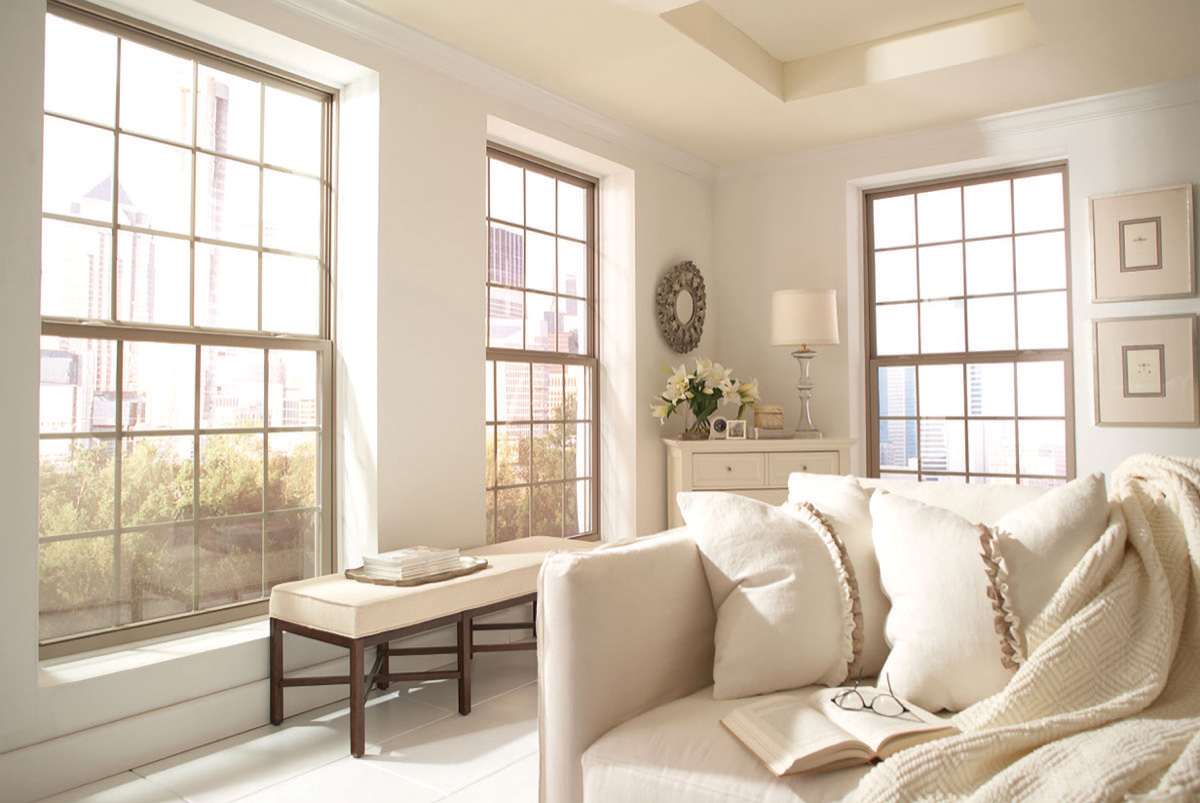 Interior view of three large tan double-hung windows featuring decorative grids and a white drywall return trim