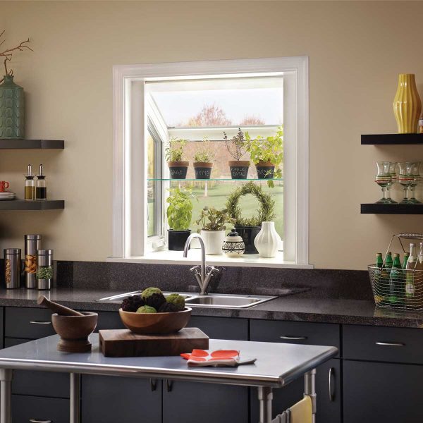 White vinyl garden window with a glass plant shelf, indoor herb garden, and black kitchen cabinetry